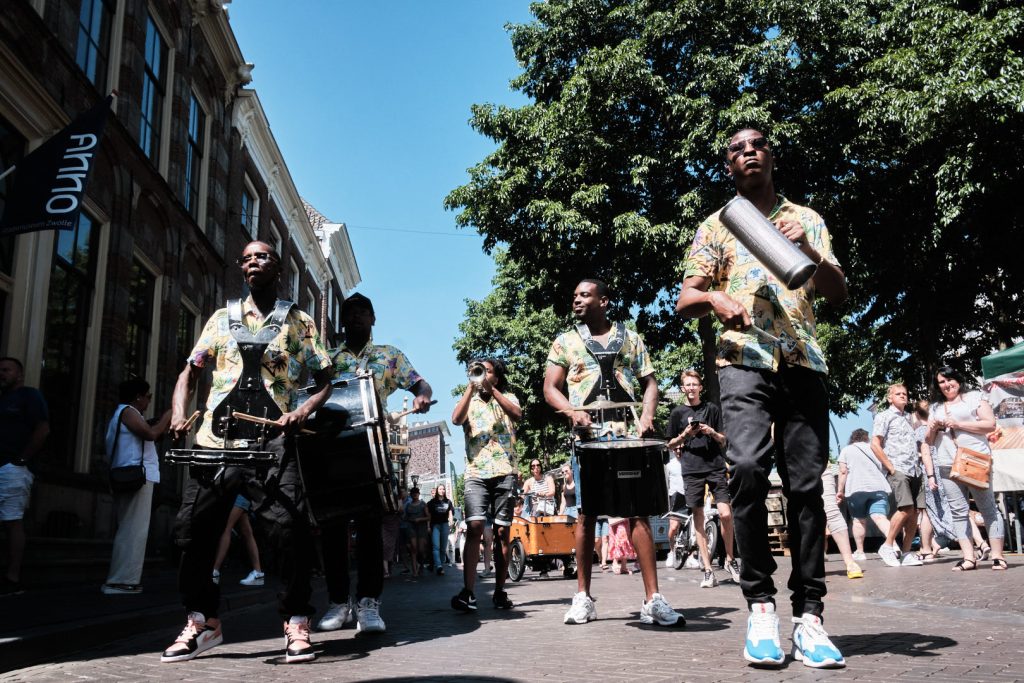 Foto van een grote groep mensen die door een stadstraat wandelen.